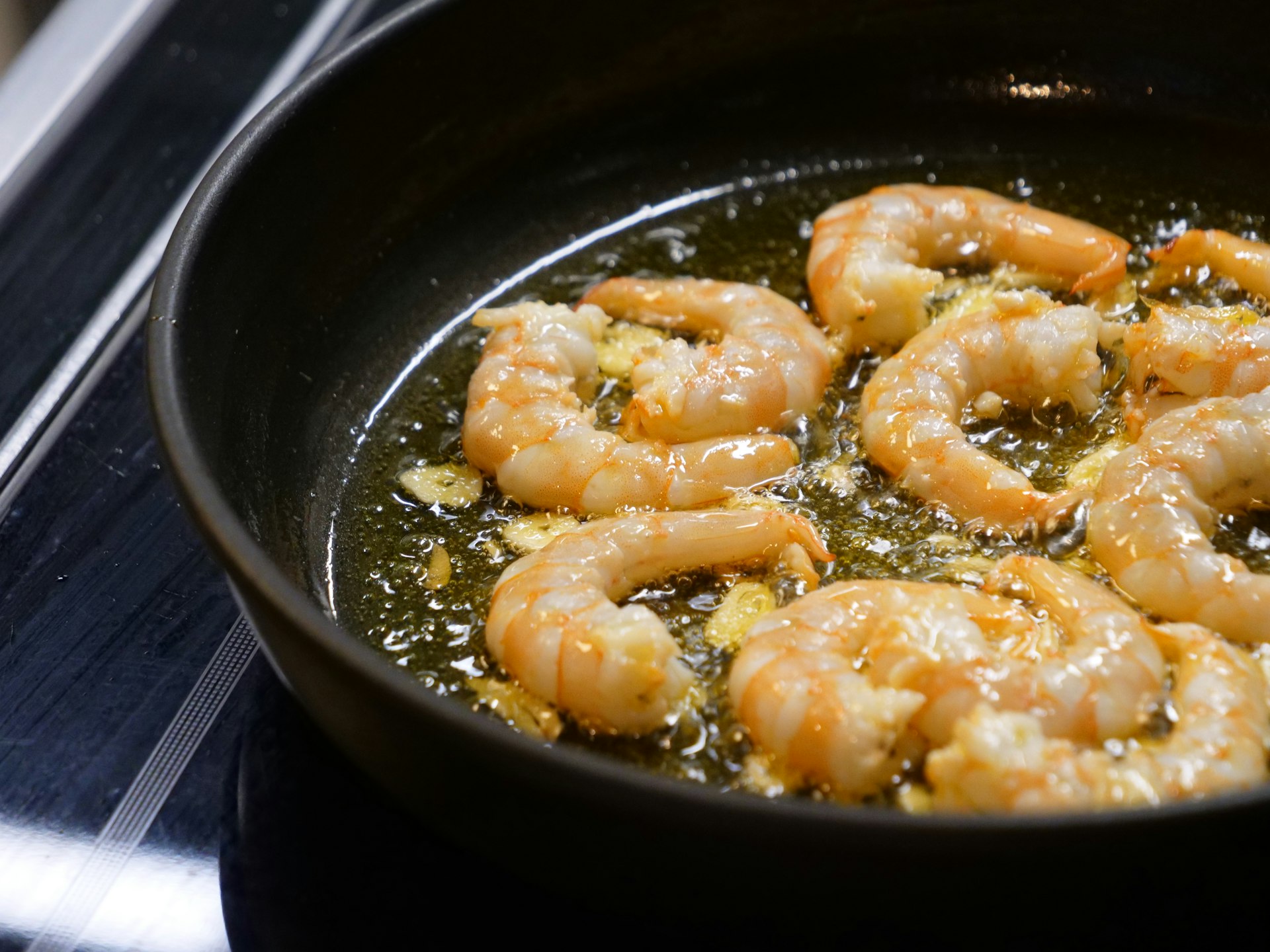 Garnalen bakken in een koekenpan met knoflook en Spaanse kruiden
