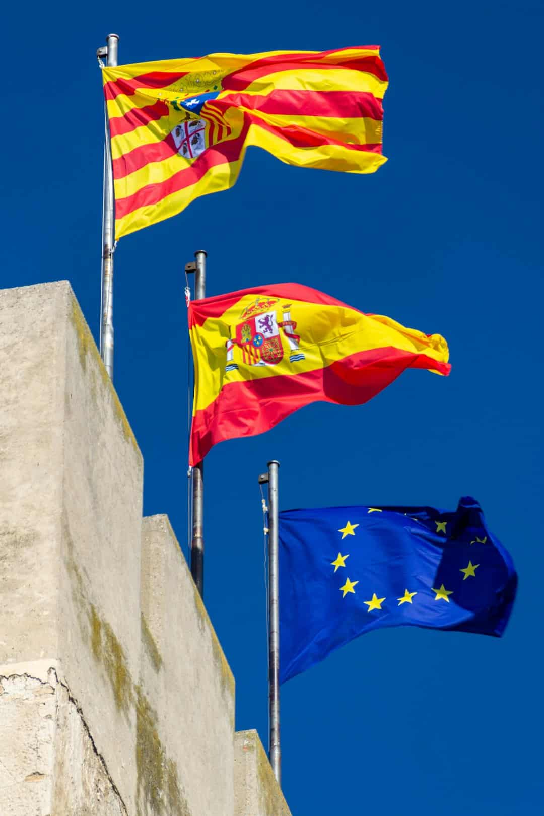 Vlaggen van een Spaanse autonome regio naast de Spaanse en EU vlag, vermogensbelasting verschilt per autonome regio