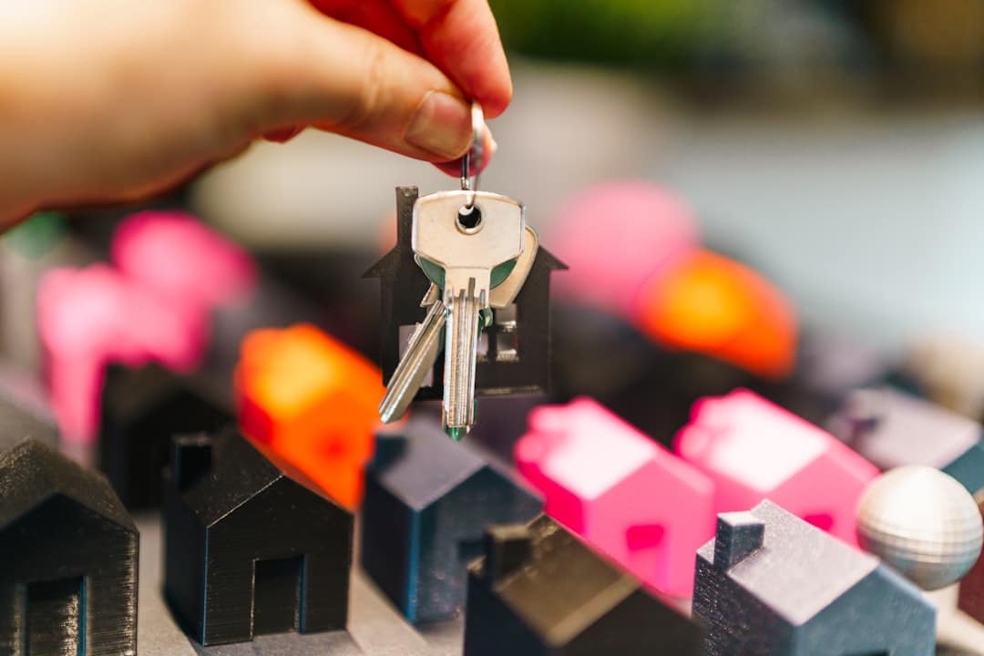 Hand houdt huissleutels vast boven miniatuur huisjes, symbool voor aankoop van een huis in Spanje met hypotheek