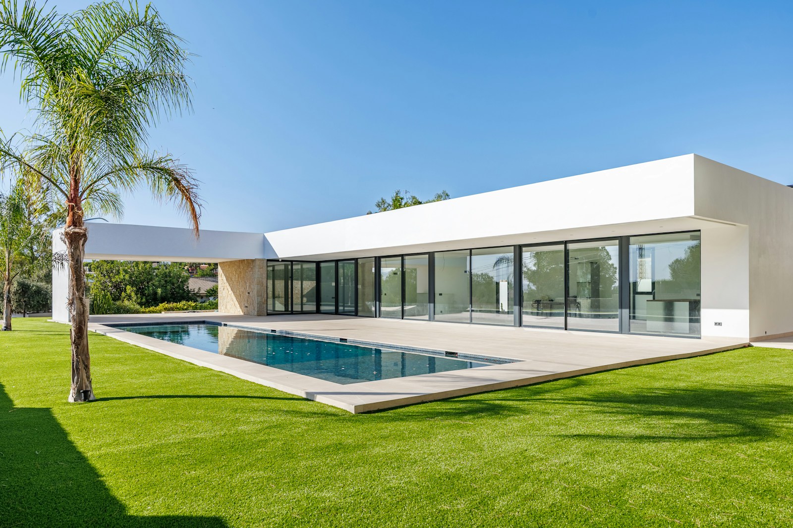 Moderne witte Spaanse villa met zwembad en palmboom, ideaal als vakantiehuis kopen in Spanje aan de Costa